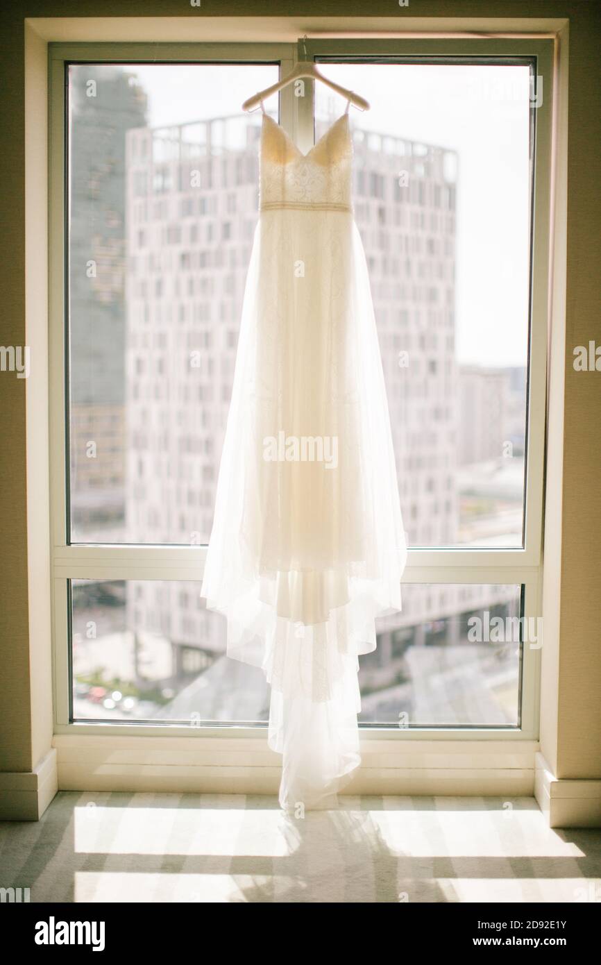 Un abito da sposa bianco appeso all'appendiabiti. Foto Stock