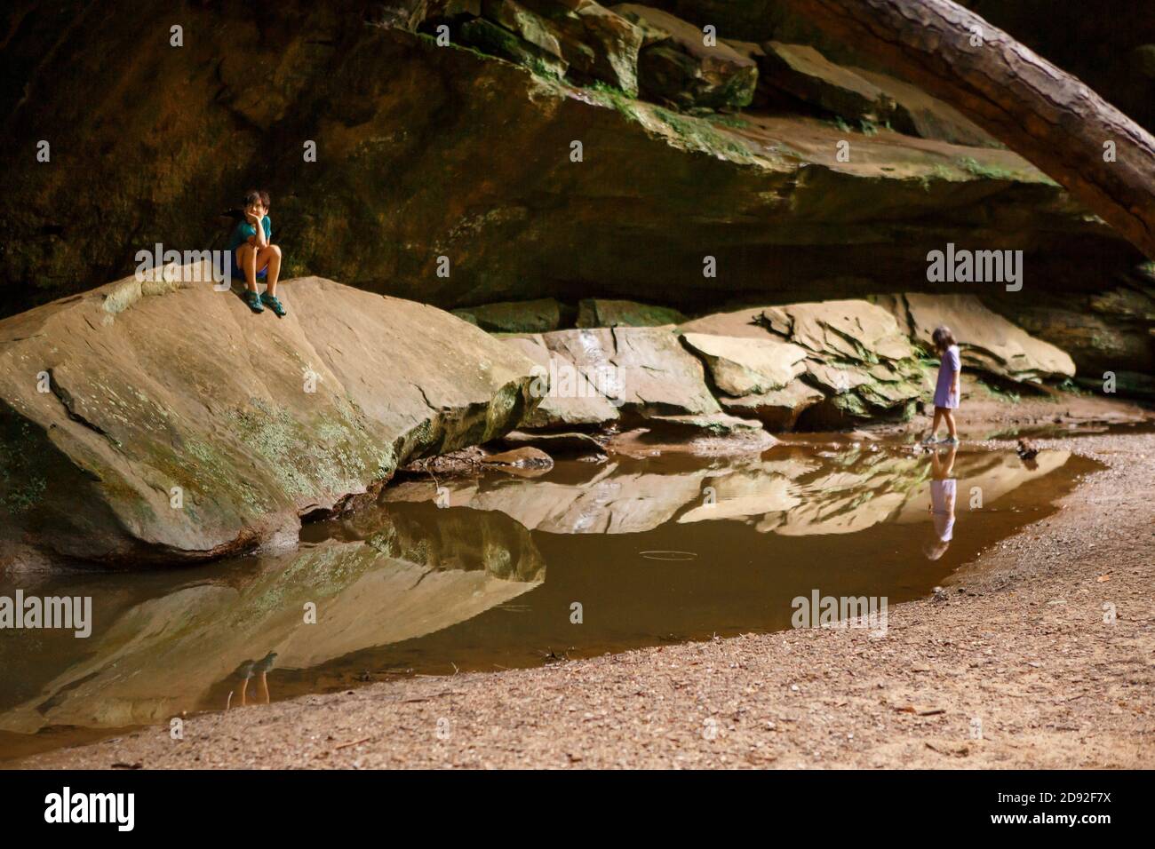 Due bambini giocano tranquillamente in una gola di arenaria da un piscina riflettente Foto Stock