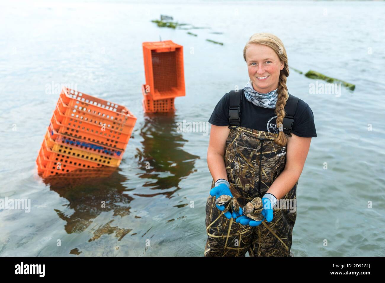 allevatore femminile di molluschi in acqua che tiene ostriche in mani Foto Stock