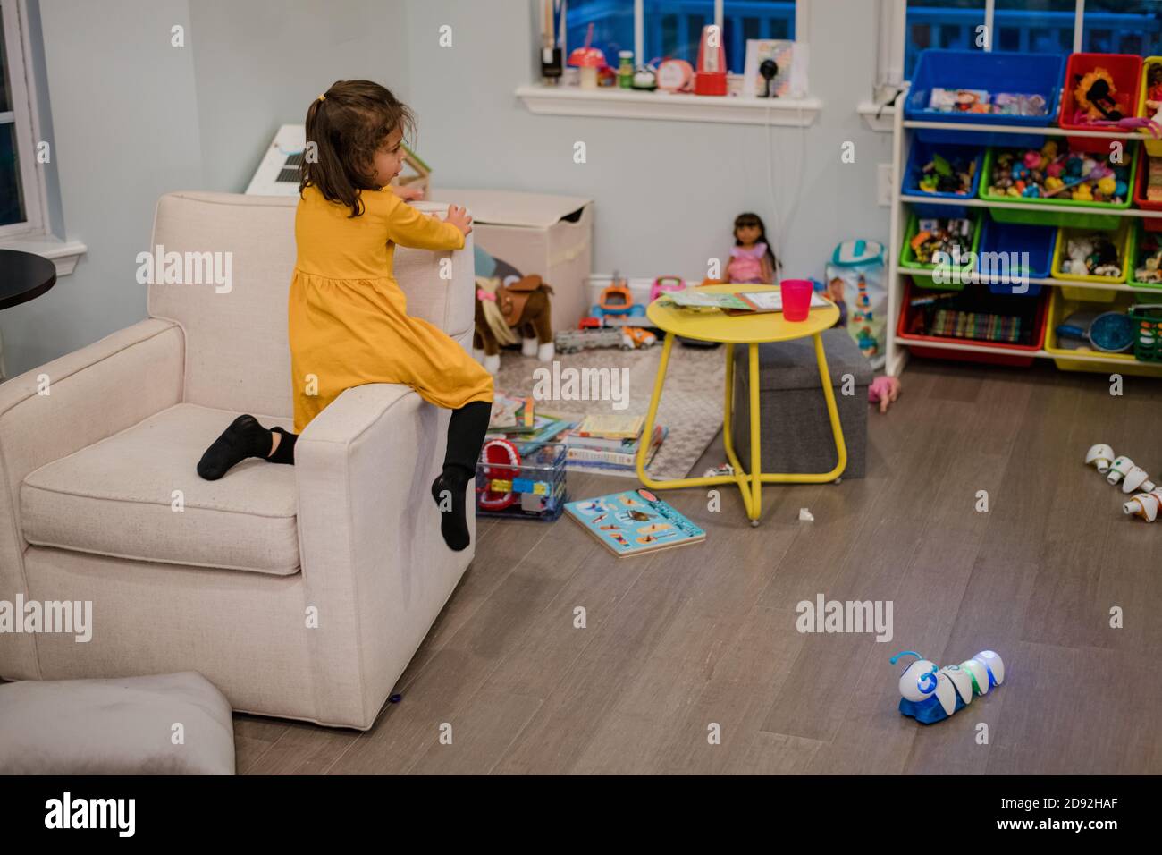 bambina che sale sulla sedia in sala giochi Foto Stock