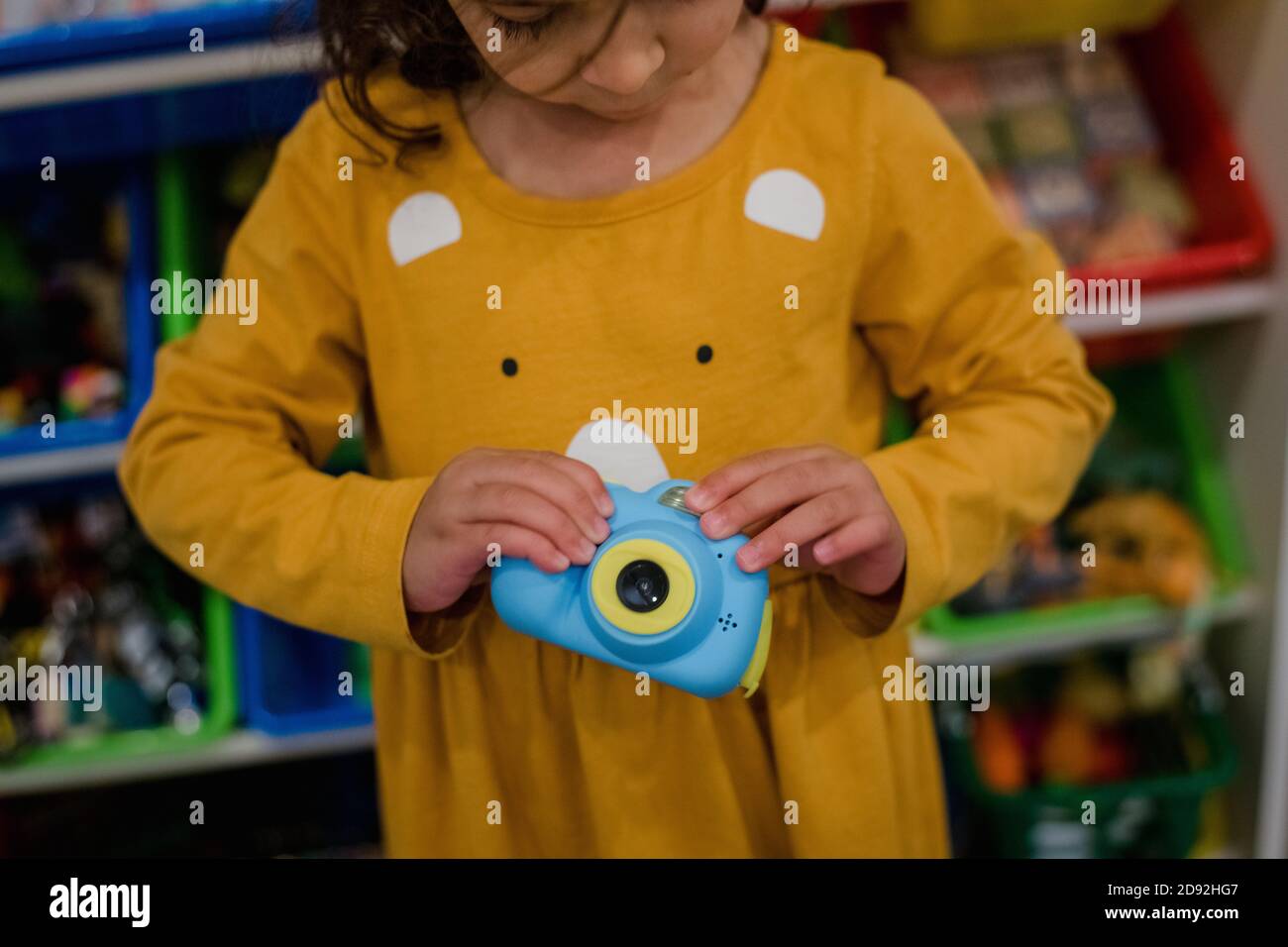 bambina che tiene una macchina fotografica giocattolo blu Foto Stock