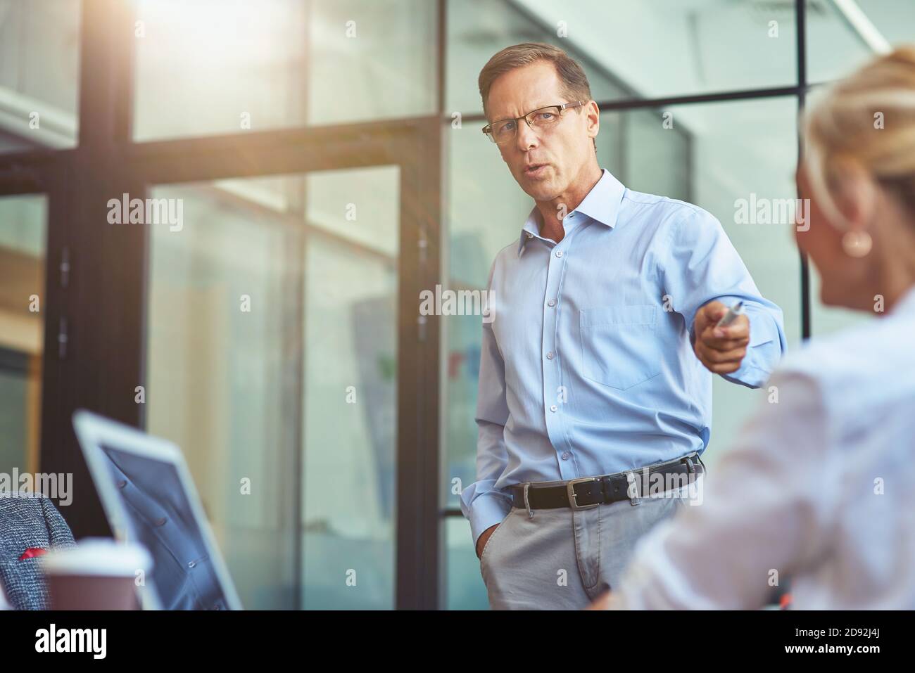 Uomini d'affari maturi concentrati a discutere qualcosa con la collega femminile mentre lavorano insieme nell'ufficio moderno Foto Stock