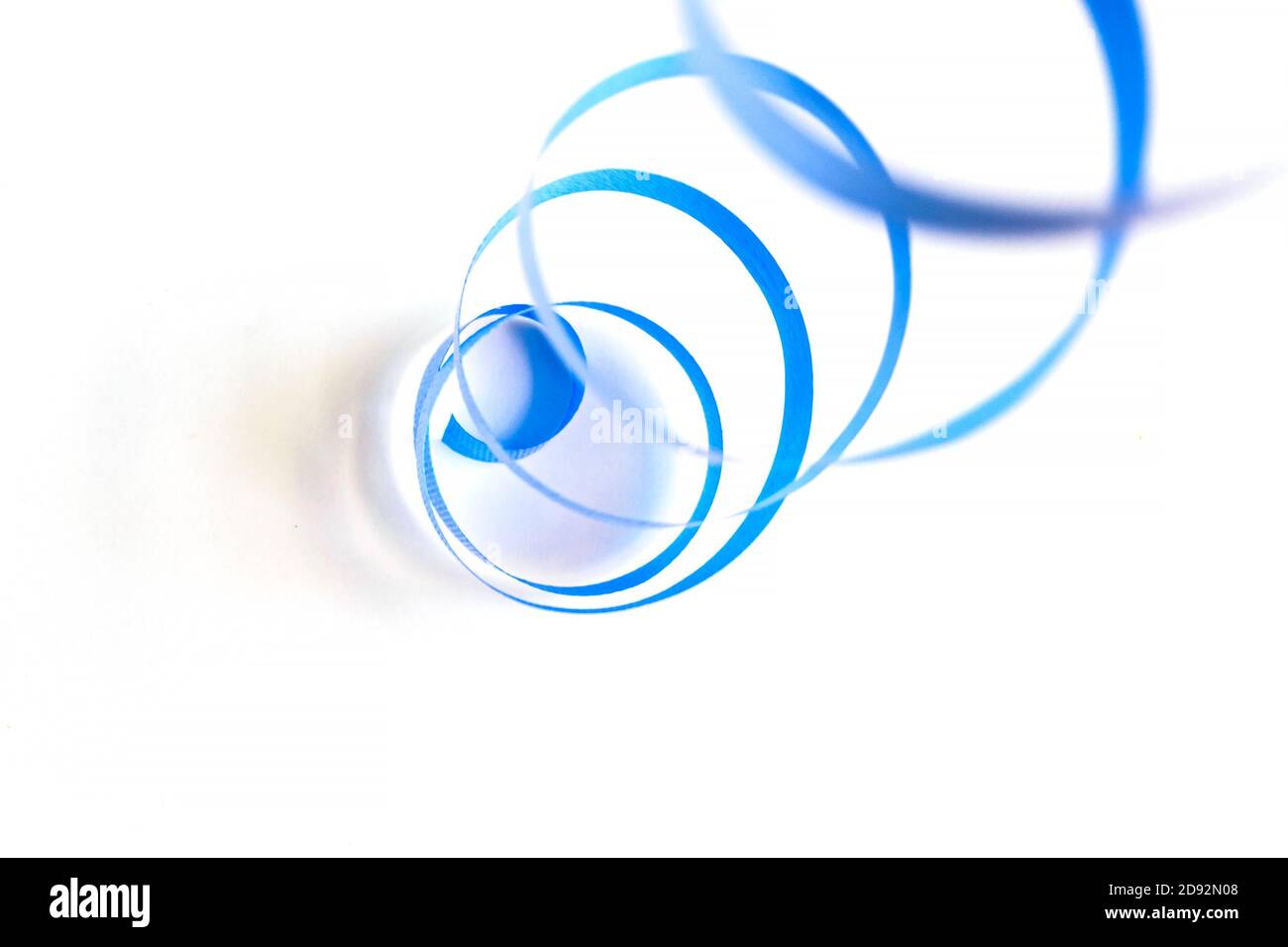 Vista astratta dall'alto del nastro arricciante blu per il confezionamento di oggetti d'arte e artigianato su sfondo bianco. Messa a fuoco selettiva morbida Foto Stock