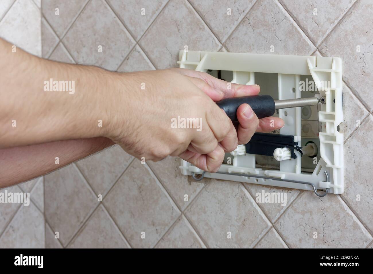 Mani del riparatore svitando una scatola di wc a filo di vite per fissare bagno guardaroba Foto Stock