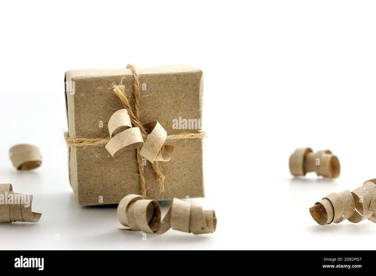 confezione regalo avvolta in carta kraft e corda di sacco legato su uno sfondo bianco, fuoco selettivo Foto Stock