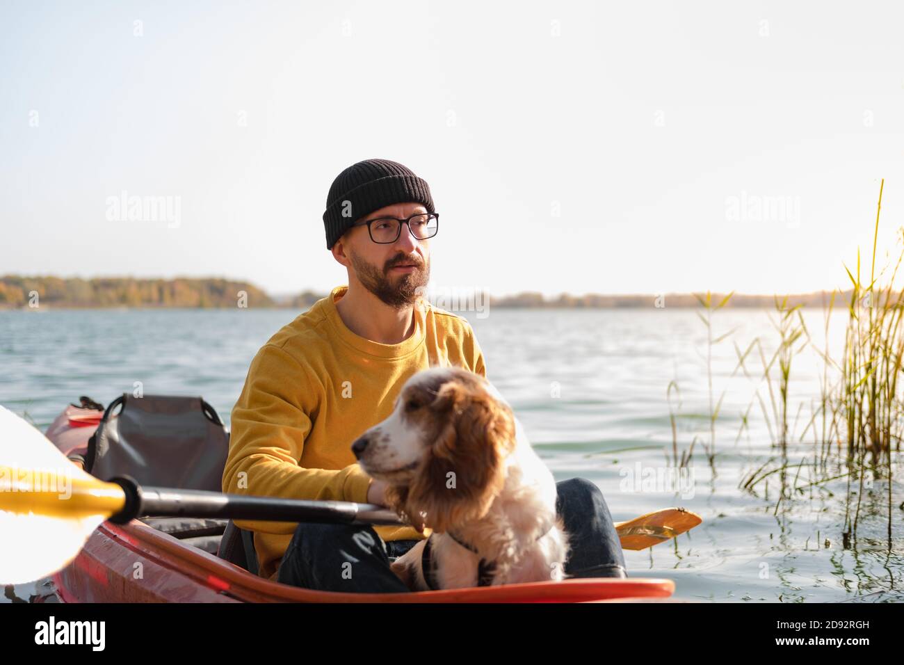 Uomo con un cane in canoa sul lago. Giovane uomo con spaniel in una barca di fila di kayak, tempo libero attivo con animali domestici, compagnia, cani d'avventura Foto Stock