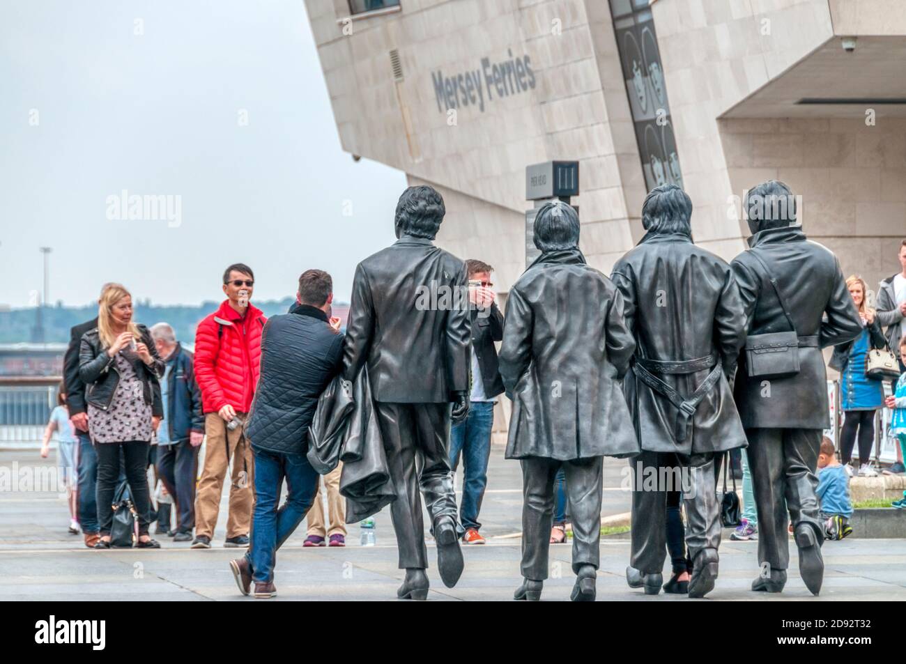 Vista posteriore delle persone che hanno scattato la loro foto con la statua dei Beatles al Liverpool Pier Head. Foto Stock