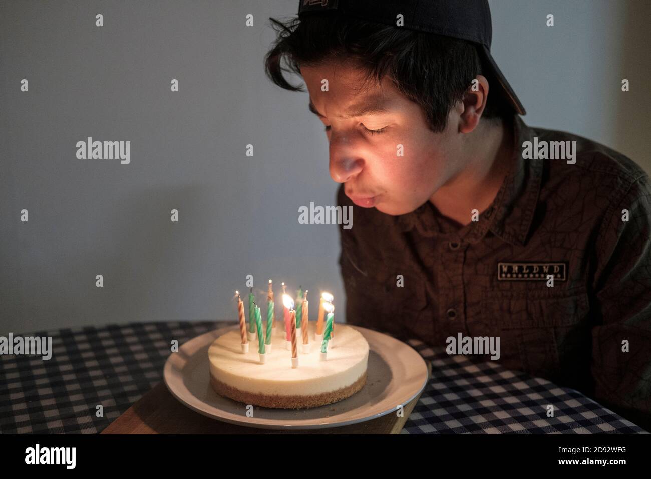 Il ragazzo adolescente soffia candele di torta di compleanno Foto Stock