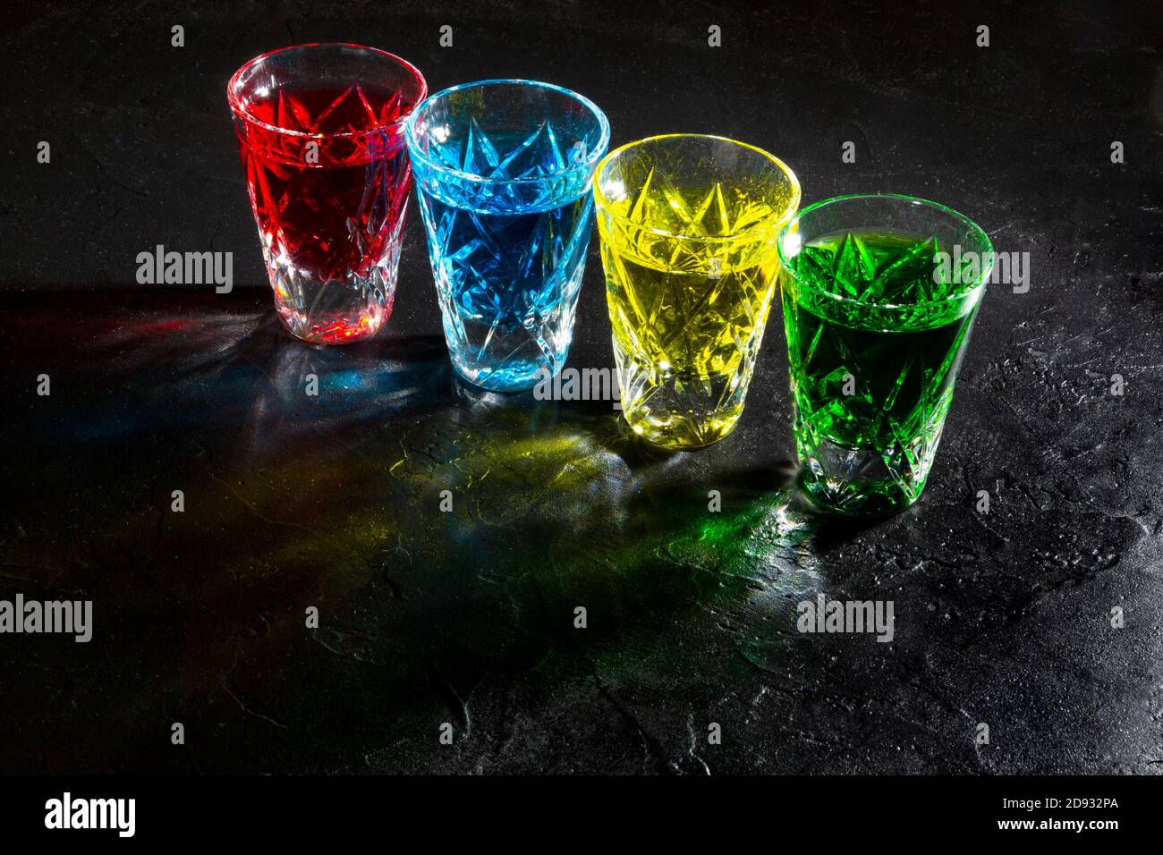 Occhiali colorati con alcol forte su sfondo scuro Foto Stock