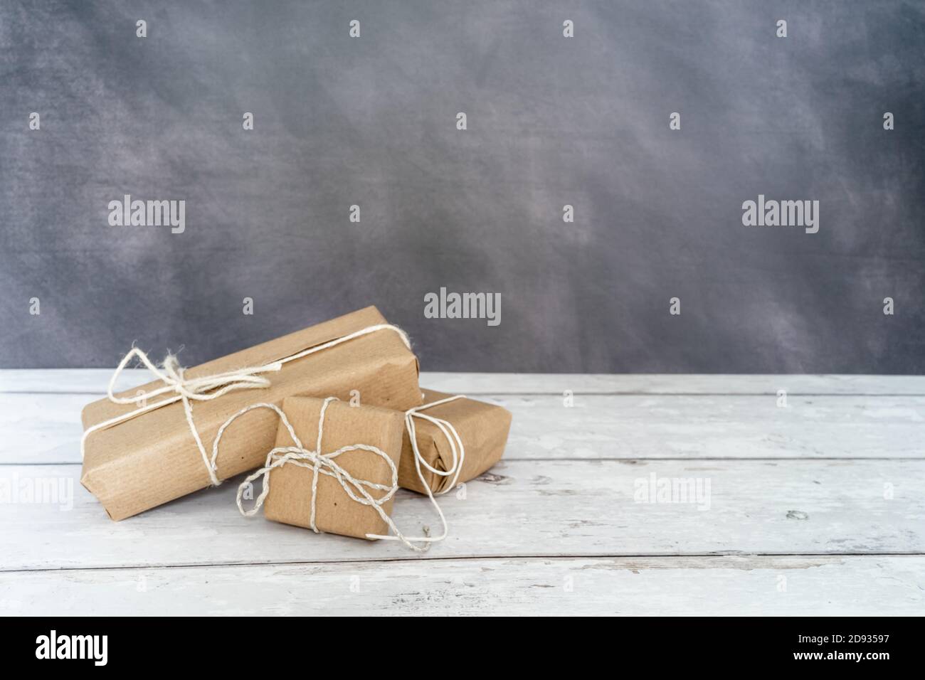 Natale e zero rifiuti, imballaggio eco-friendly. Regali avvolti in carta artigianale su un tavolo di legno su uno sfondo scuro. Natale ecologico co Foto Stock