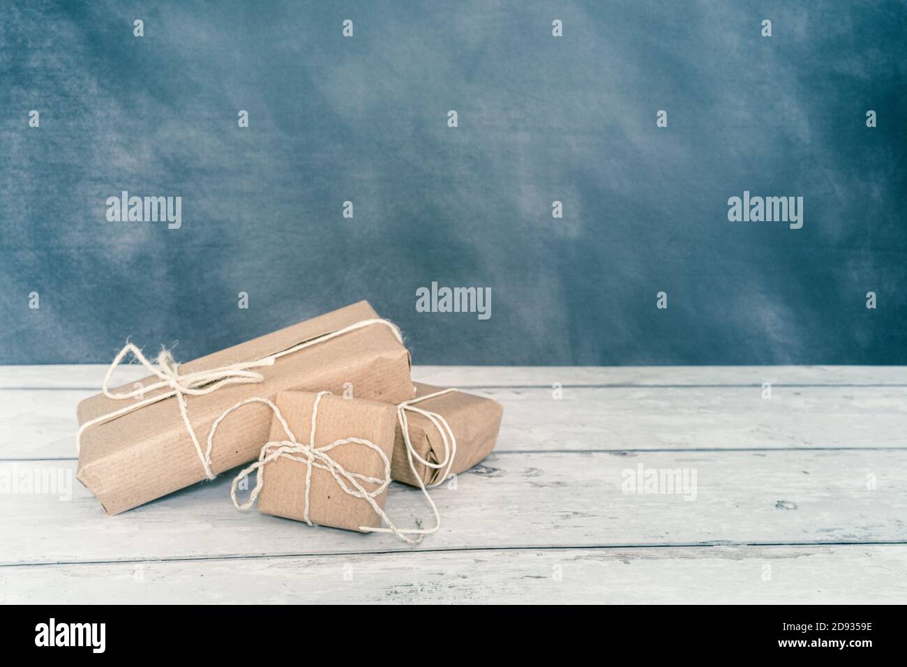 Natale e zero rifiuti, imballaggio eco-friendly. Regali avvolti in carta artigianale su un tavolo di legno su uno sfondo scuro. Natale ecologico co Foto Stock
