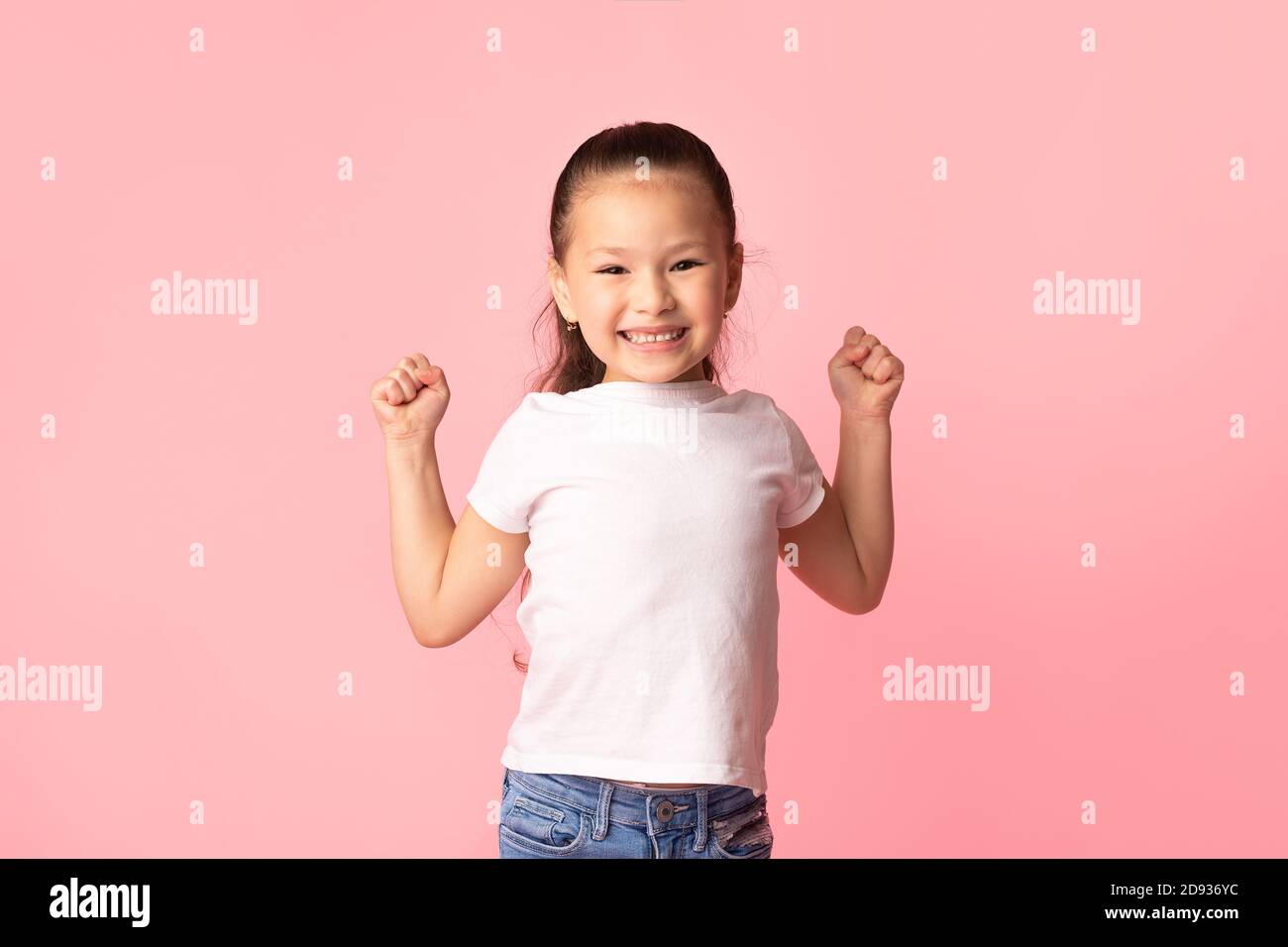 Felice ragazza asiatica agitando pugni, facendo gesto vincitore Foto Stock