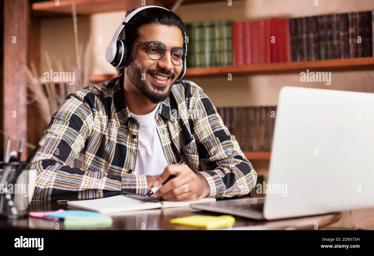 Studente indiano positivo al laptop Learning Online a casa Foto Stock