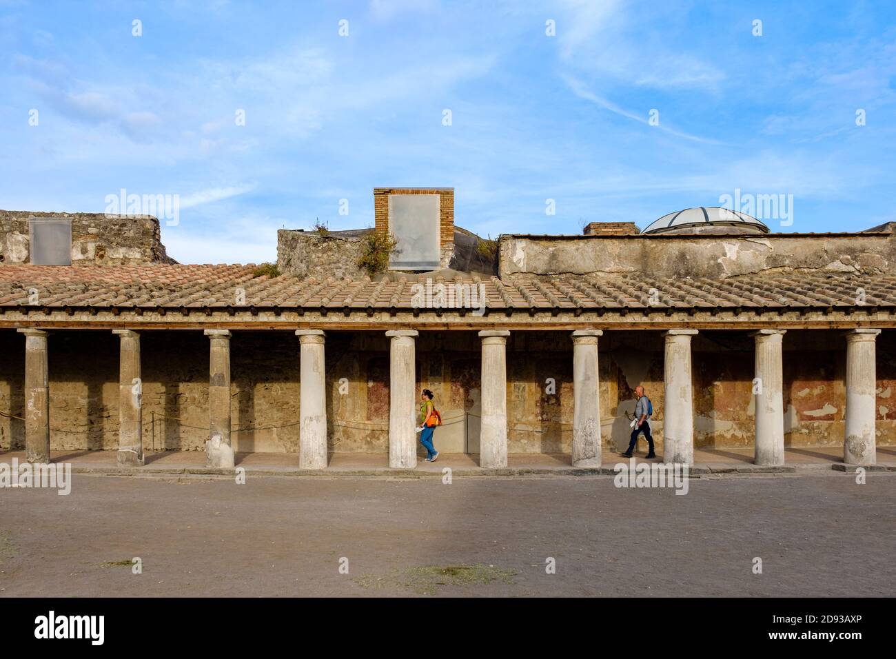Turisti che camminano tra le colonne all'esterno delle Terme Stabiane, le antiche rovine del complesso termale romano, Pompei, Campania, Italia Foto Stock