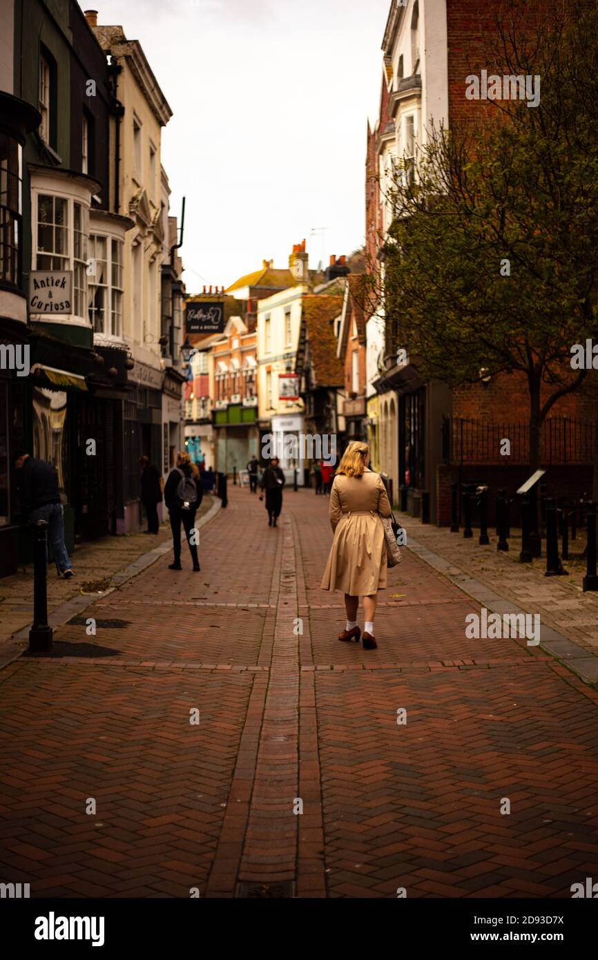 Una donna bionda in stile vintage a piedi attraverso George Street, Hastings Foto Stock