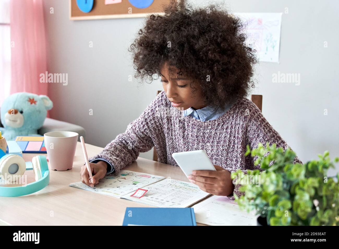 Ragazza africana di scuola di capretto che usa l'applicazione del telefono mobile in classe di apprendimento in linea a casa. Foto Stock