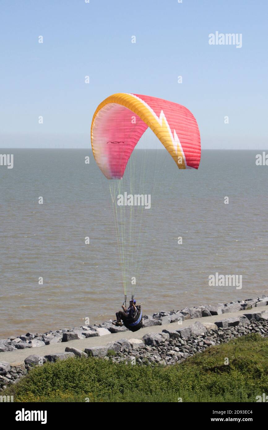 Parapendio contro un cielo blu luminoso sulla costa dell'Essex Foto Stock