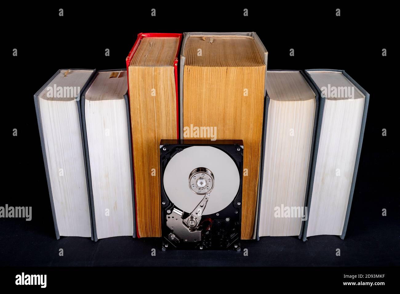 Libri cartacei e disco del computer vecchi. Supporto carta e dati digitali. Sfondo scuro. Foto Stock