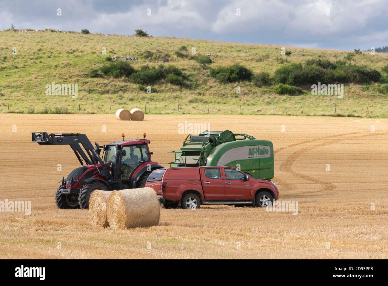 Un pick-up si trova accanto a un trattore e a una pressa McHale Durante le operazioni di raccolta ad Aberdeenshire Foto Stock