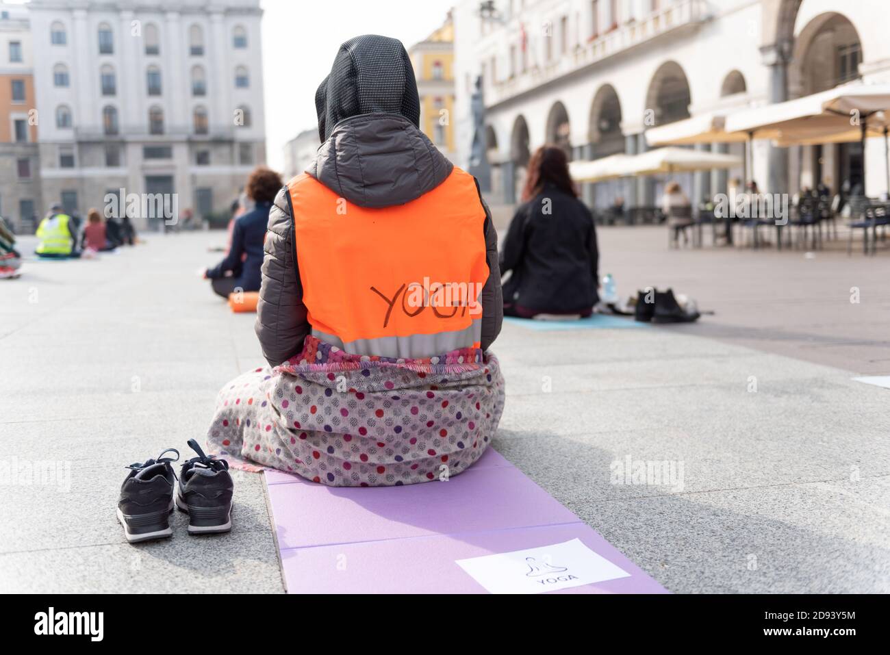 Insegnanti di yoga che protestano contro il blocco e le restrizioni del Covid-19 in una piazza a Brescia, Italia. Le persone che si siedono sul tappeto fitness e sono io Foto Stock