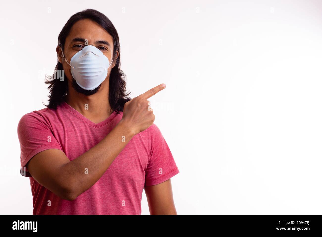 Giovane felice latino con maschera medica su sfondo bianco. Spazio di copia. Concetto di coronavirus. Foto Stock