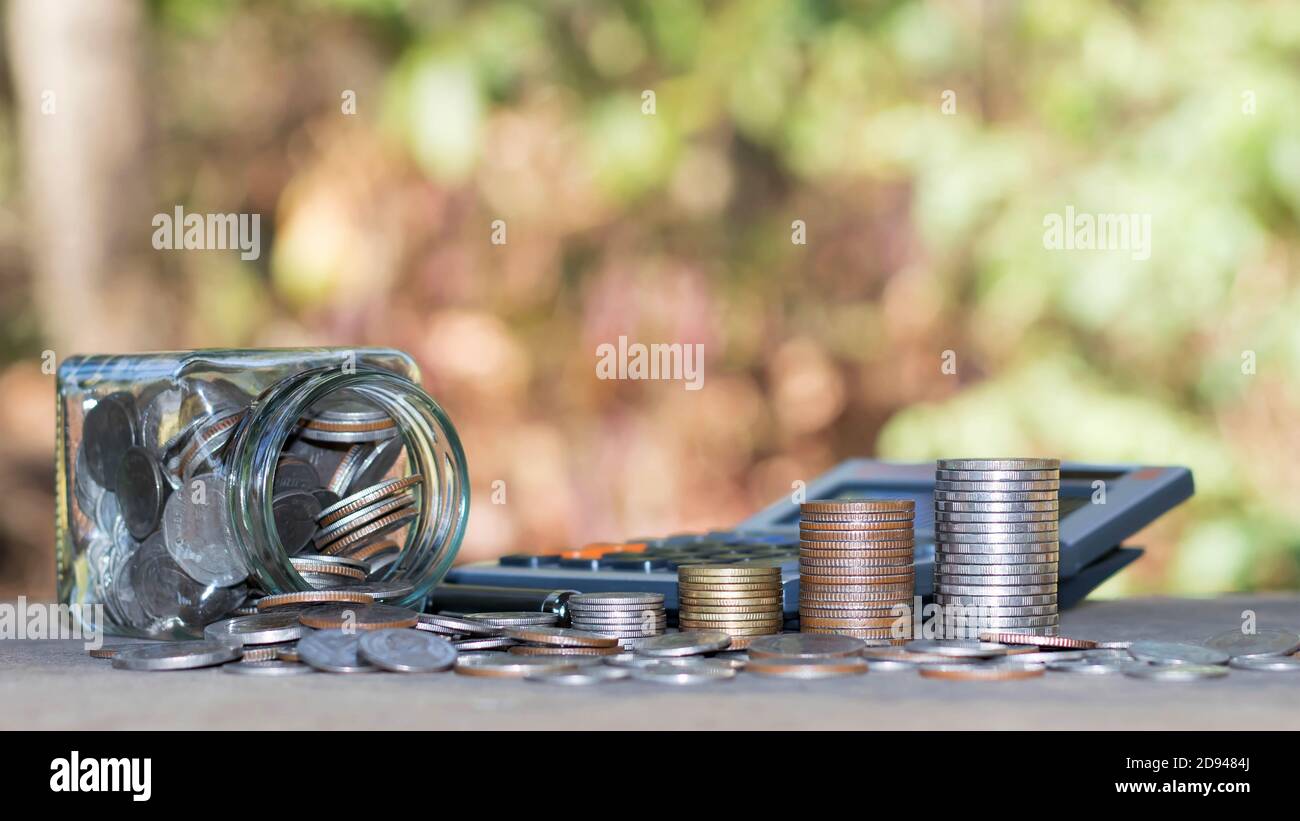 Monete o denaro su calcolatrici, concetti di contabilità finanziaria e risparmiare denaro. Foto Stock