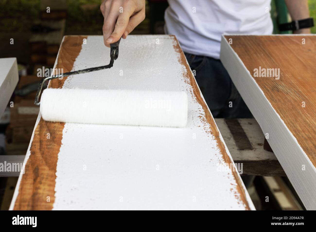 Uomo verniciatura tavole di legno con rullo di vernice e vernice bianca  Foto stock - Alamy