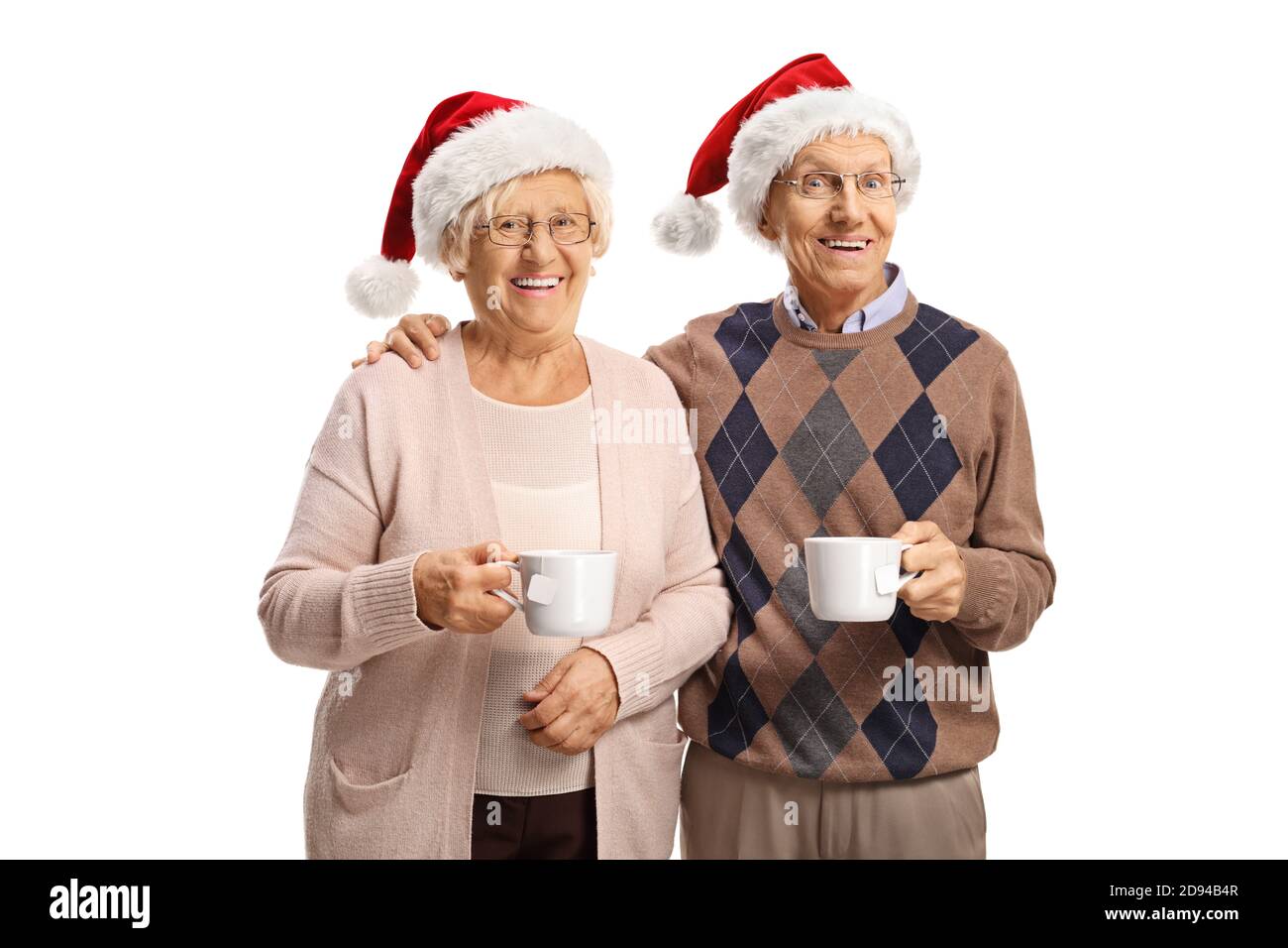 Coppia anziana che tiene tazze da tè e indossa cappelli babbo natale isolato su sfondo bianco Foto Stock
