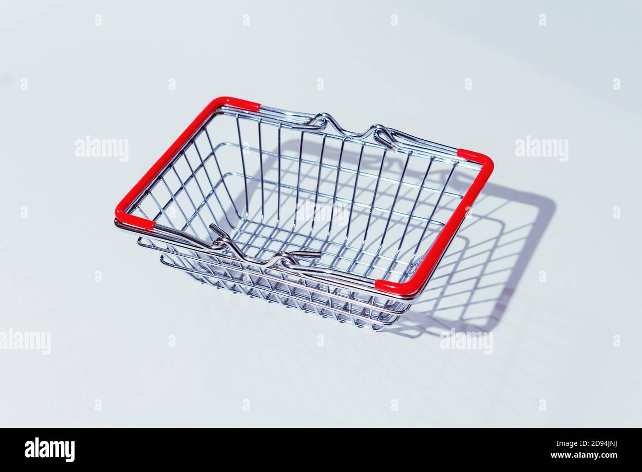 Cestino vuoto in metallo con maniglie rosse su sfondo grigio. Salario vivente. Ombre dure. Foto Stock