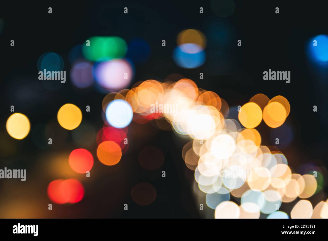 Vista sulla strada offuscata della città di notte con il bokeh vibrante chiaro su sfondo scuro Foto Stock