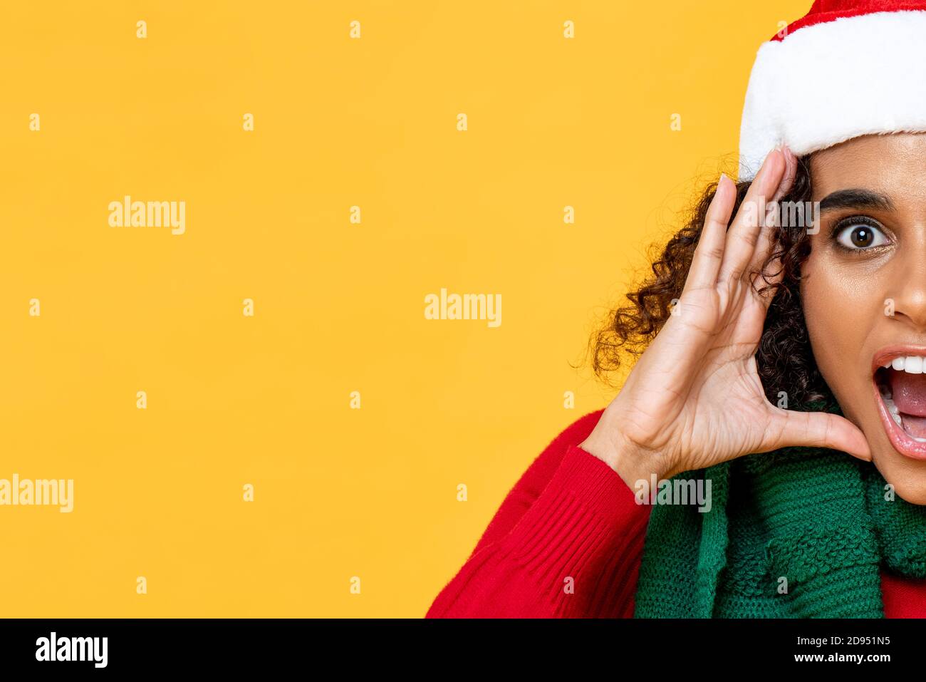 Mezza faccia di donna scioccata che indossa il vestito di Natale che urla dentro sfondo di studio isolato giallo con spazio di copia Foto Stock