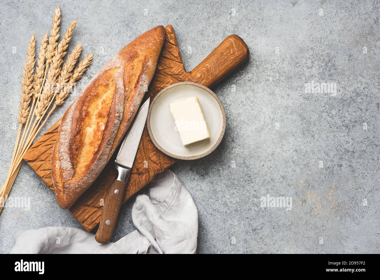 Pane fresco baguette e burro su fondo di cemento. Spazio di copia della vista superiore per il testo Foto Stock