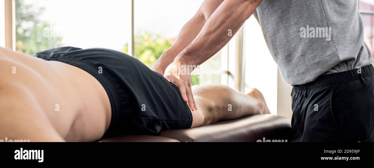 Terapista maschile che dà massaggio alle gambe al paziente atleta a letto in clinica Foto Stock