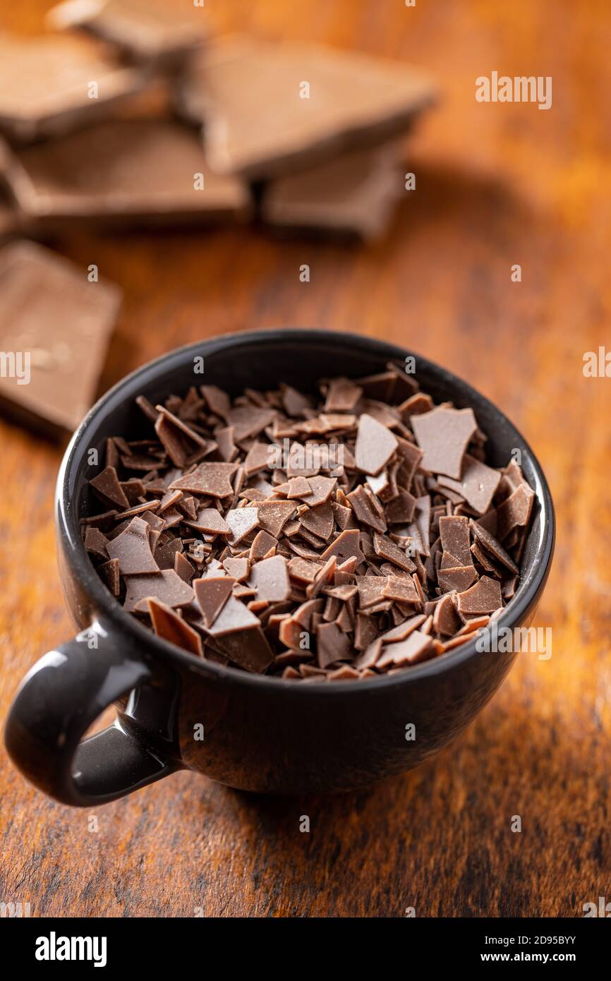 Cioccolato fondente grattugiato. Scaglie di cioccolato in tazza su tavolo  di legno Foto stock - Alamy