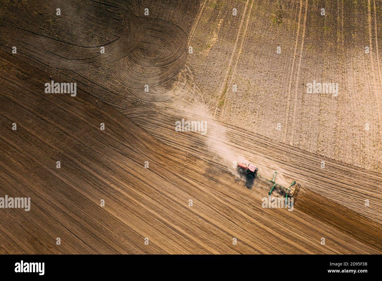 Vista aerea. Campo di aratura del trattore. Inizio della stagione di primavera agricola. Coltivatore trainato da un trattore in campagna paesaggio rurale. Polvere Foto Stock