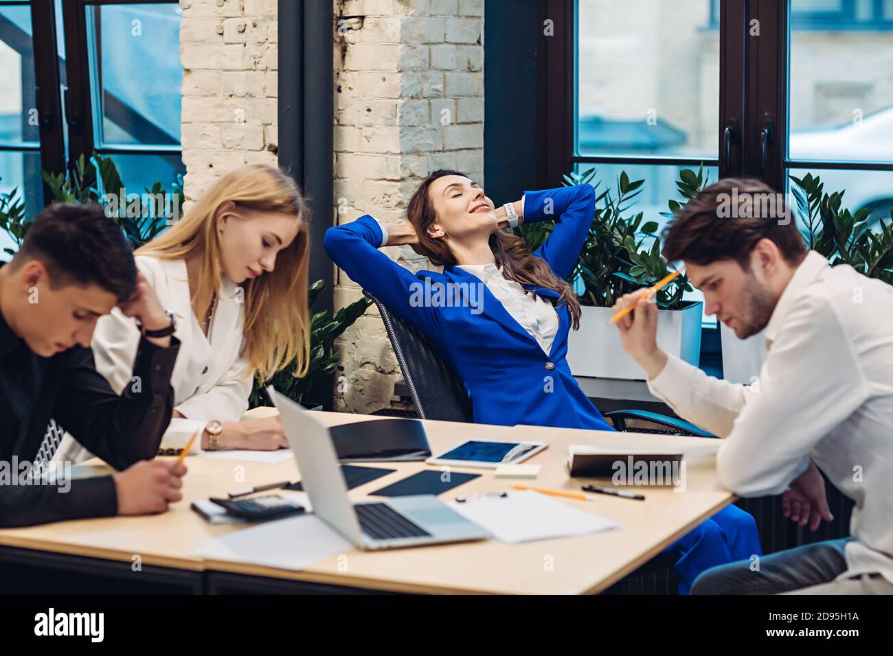 La donna d'affari si rilassa mentre i suoi colleghi lavorano Foto Stock