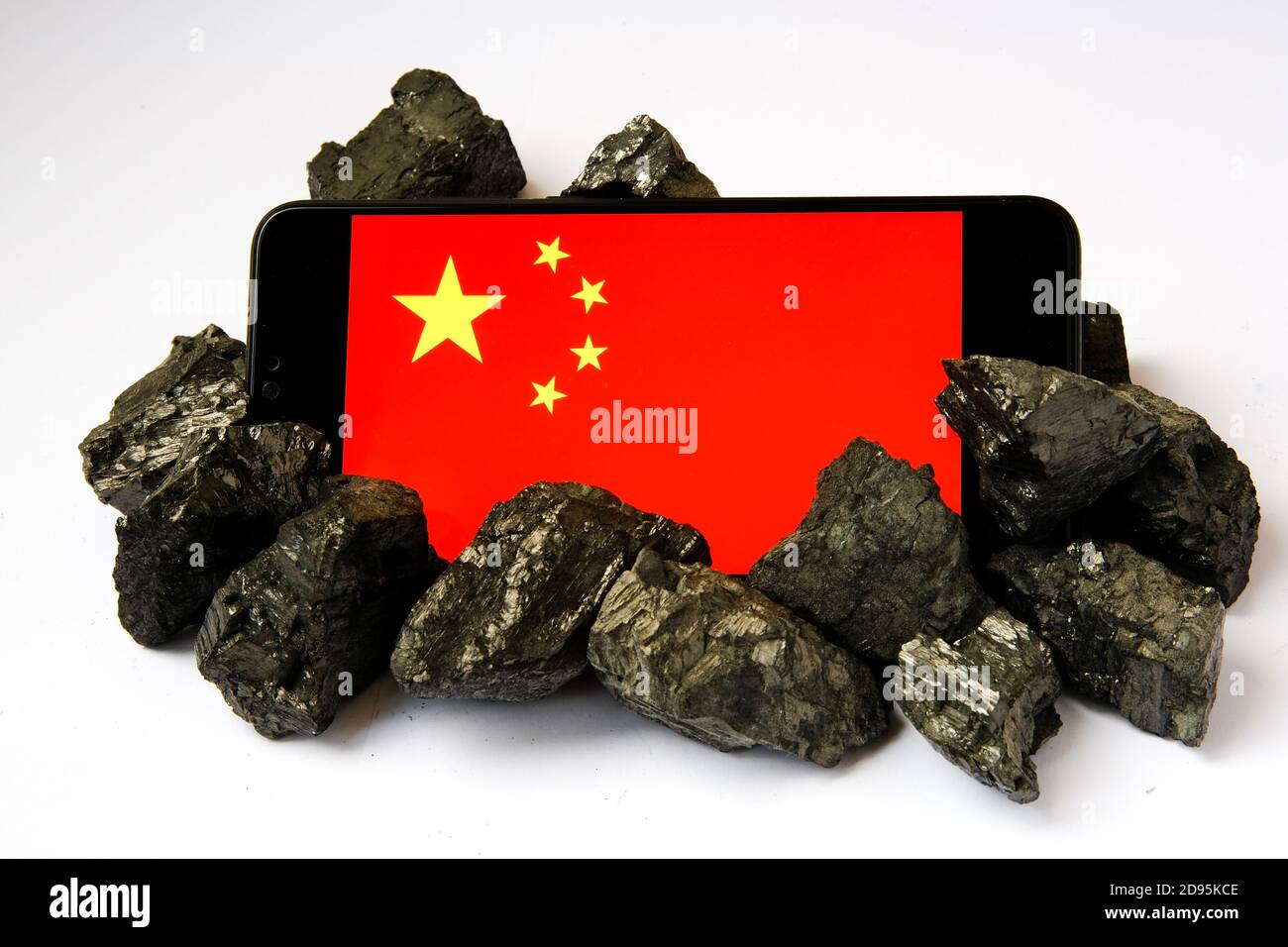 La dipendenza della Cina dal carbone. Concetto. L'industria e la tecnologia cinesi si affidano all'estrazione del carbone e del carbone. Bandiera della Cina visto sullo smartphone circondato da carbone Foto Stock