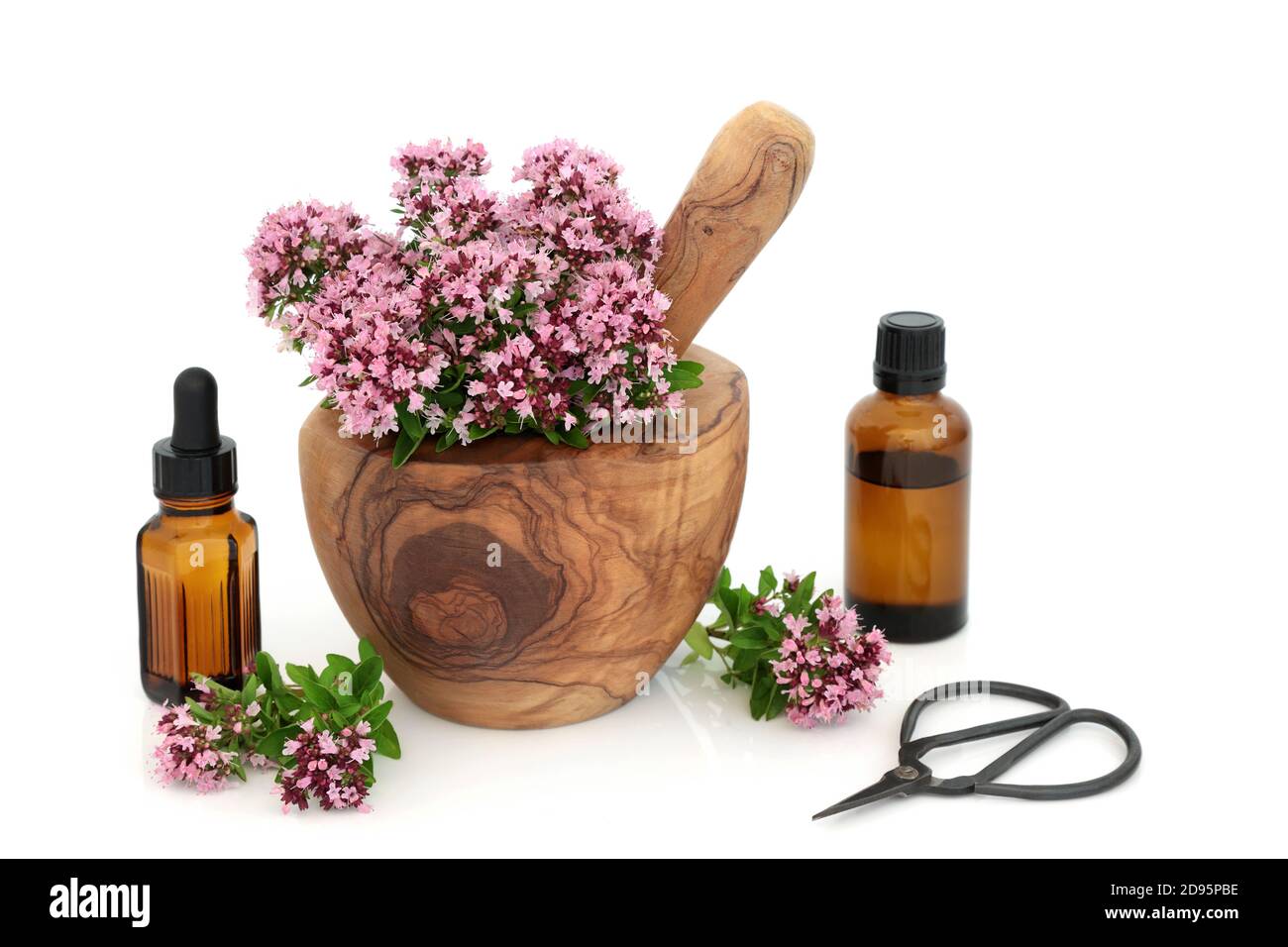 Origano fiori e foglie di erbe in mortaio con pestello con bottiglie d'olio essenziali. Usato come condimento di cibo & in medicina di erbe. Può alleviare i sintomi dell'IBS. Foto Stock