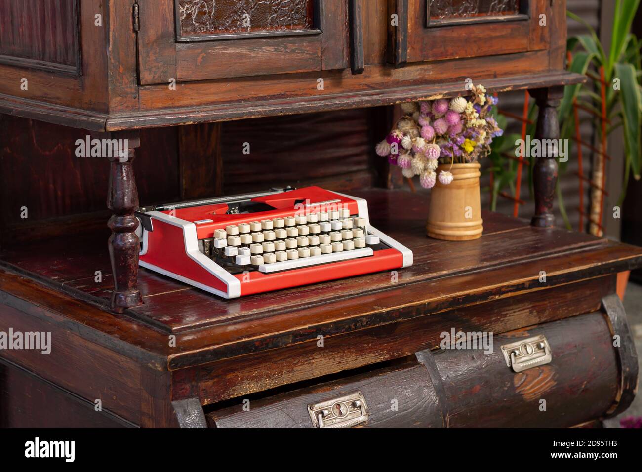 Macchina da scrivere rossa d'epoca con fiori su legno vecchio armadio scolpito Foto Stock