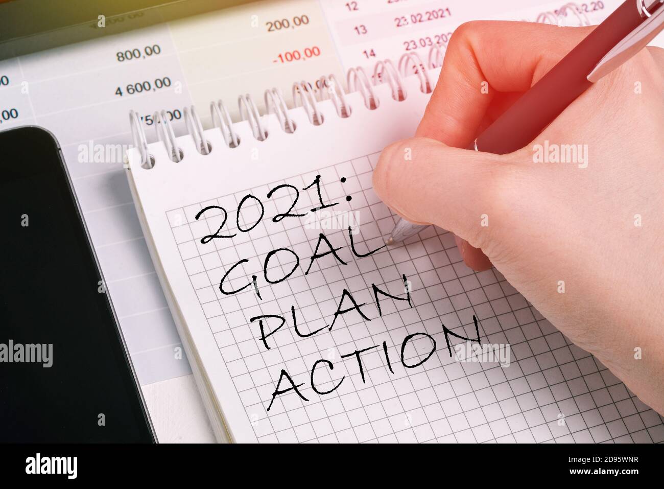 Il lavoratore di ufficio scrive un elenco per 2021 in un notebook. Concetto di pianificazione, impostazione degli obiettivi Foto Stock