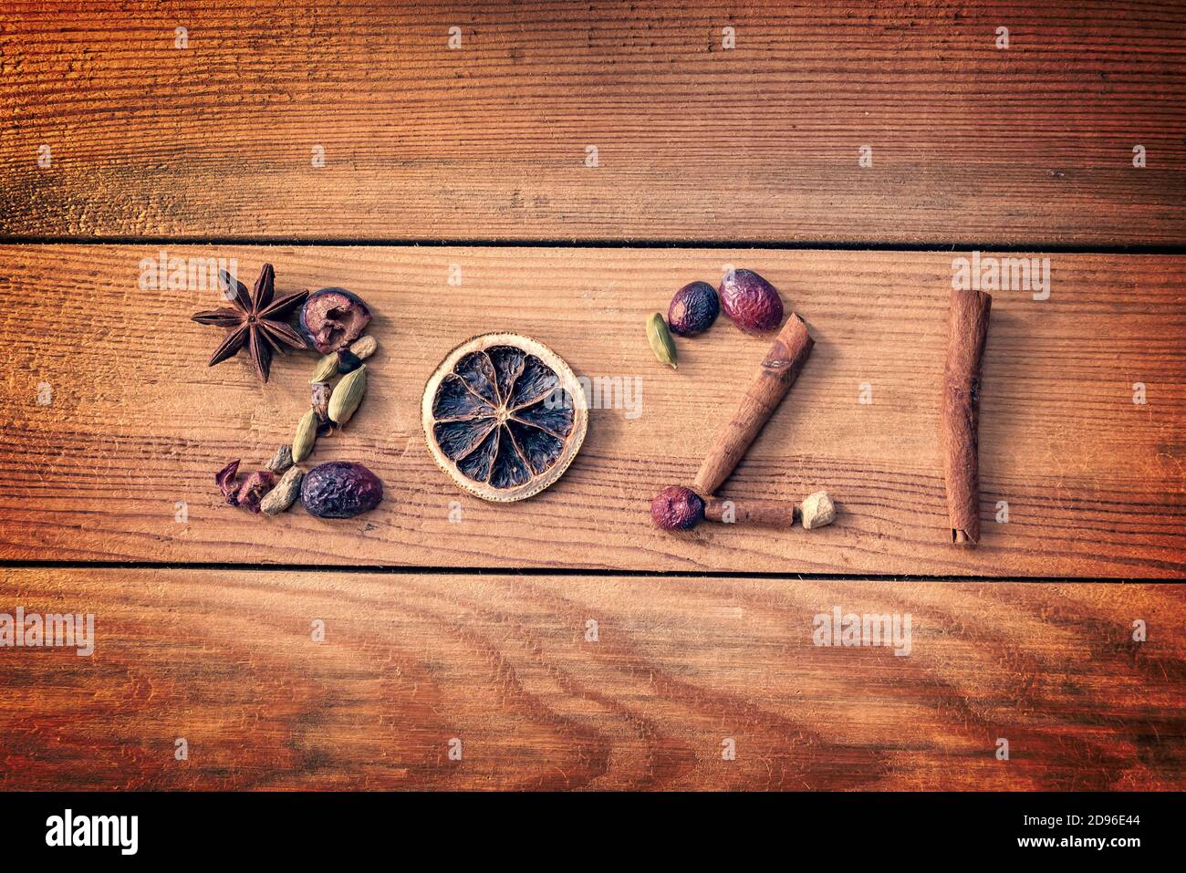 2021 scritto con spezie natalizie e frutta secca su sfondo ligneo, biglietto d'auguri per il nuovo anno Foto Stock