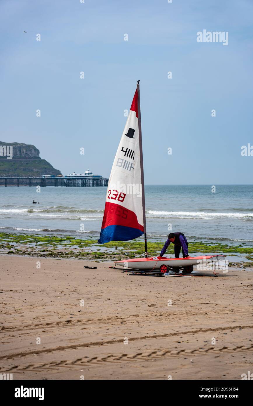 Un marinaio ririca la loro dingy del topper navigare dalla costa occidentale, Llandudno, Galles Foto Stock