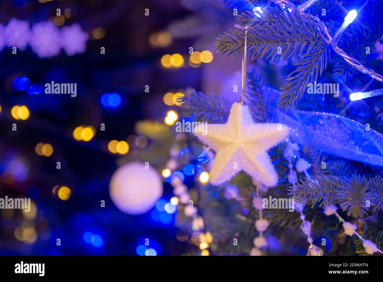 Stella bianca appesa su un albero di Natale, ornamenti di Natale di notte, luci di vacanza bianche e dorate Foto Stock
