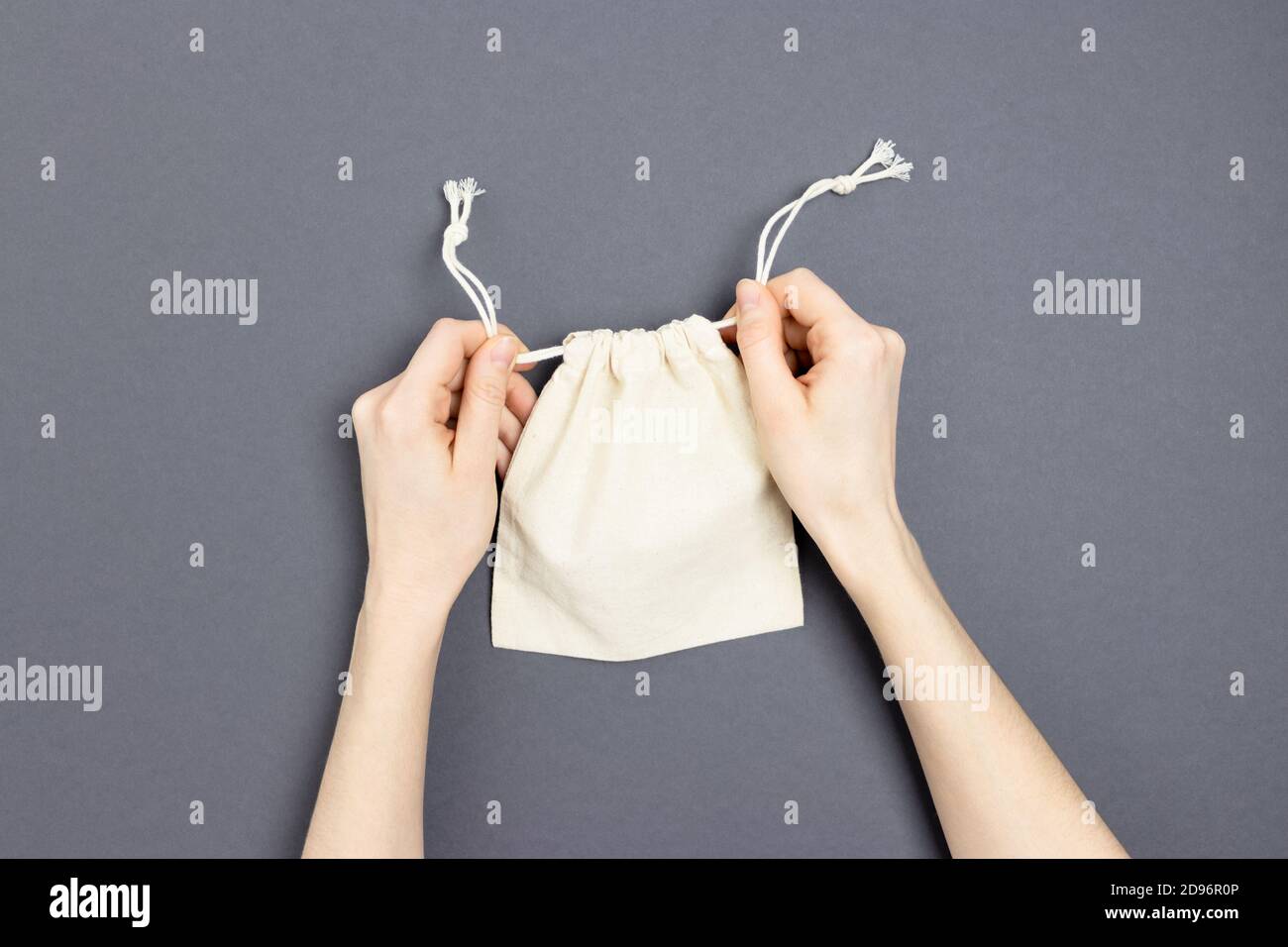 Le mani femminili stringano i lacci su una piccola borsa di tela. Foto Stock