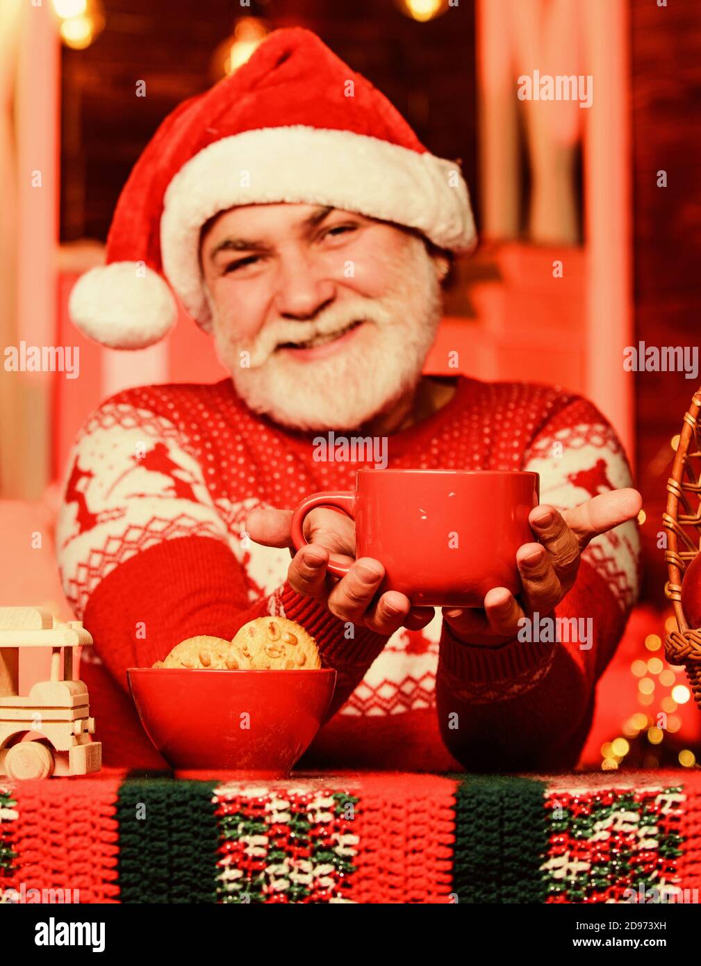 Festa invernale. Bevande calde. Ricetta di cacao di Natale. Garland illumina un'atmosfera accogliente. Sentirsi bene a casa. Uomo anziano Babbo Natale bere tè. Celebrazione del nuovo anno. Nonno con tazza. Foto Stock