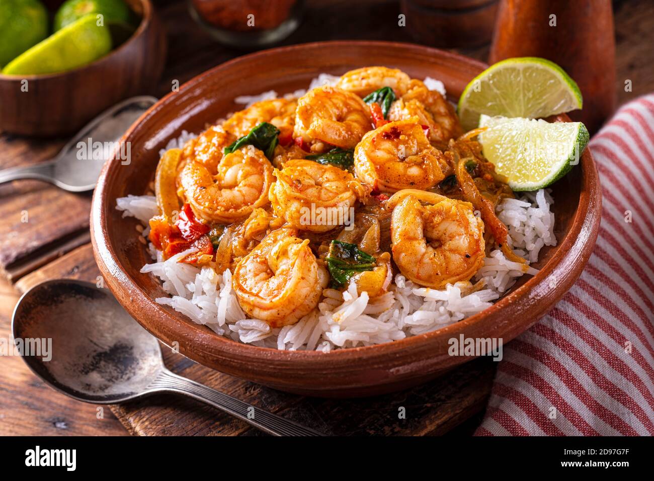 Una ciotola di delizioso masala di curry di gamberi in stile indiano del sud con pomodoro, spinaci, riso basmati e lime. Foto Stock