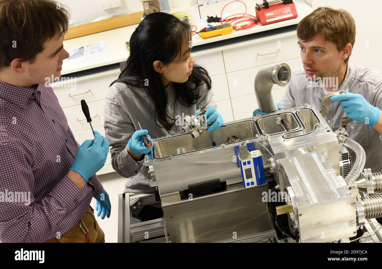 20 ottobre 2020, Sassonia, Lipsia: Presso l'Istituto Wilhelm Ostwald per la chimica fisica e teorica dell'Università di Lipsia, il chimico di 33 anni Dr. Jonas Warneke collabora con i membri del suo gruppo di ricerca junior, Il chimico Ziyan Warneke e il fisico laureato Harald Knorke (l-r) su uno strumento di deposizione ionica per la deposizione di ioni gassosi sulle superfici. Dall'inizio del 2020, questo eccezionale giovane ricercatore lavora con un gruppo di giovani scienziati come "spirito libero" all'università. Il gruppo è alla ricerca di modi per costruire molecole personalizzate Foto Stock
