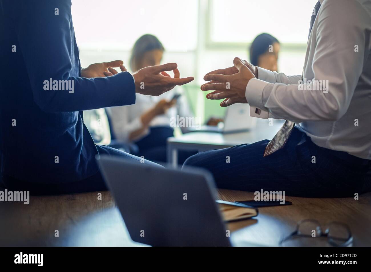 Riunione aziendale dei partner. Primo piano di mani umane che gestiscono durante la discussione in primo piano. Gli impiegati lavorano su sfondo sfocato. Foto Stock