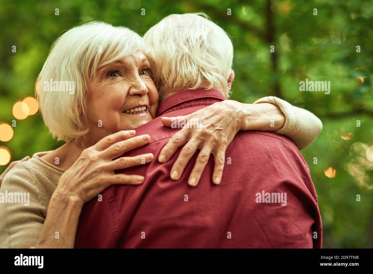 Vita in su di donna anziana sorridente abbracciando il suo sposo mentre passa il tempo nel giardino. Concetto di famiglia Foto Stock