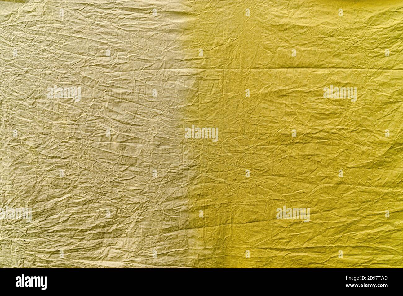 Un pezzo di tessuto di cotone sminuzzato in due tonalità gialle, tinto con diversi coloranti vegetali. Una parte del materiale: Giallo chiaro, l'altra più scura Foto Stock